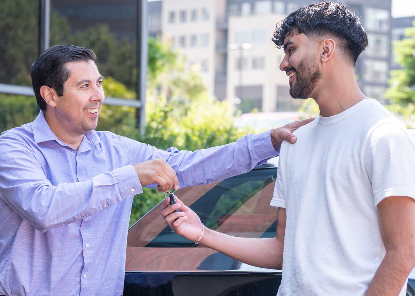 Father smiling as he hands keys to teen son