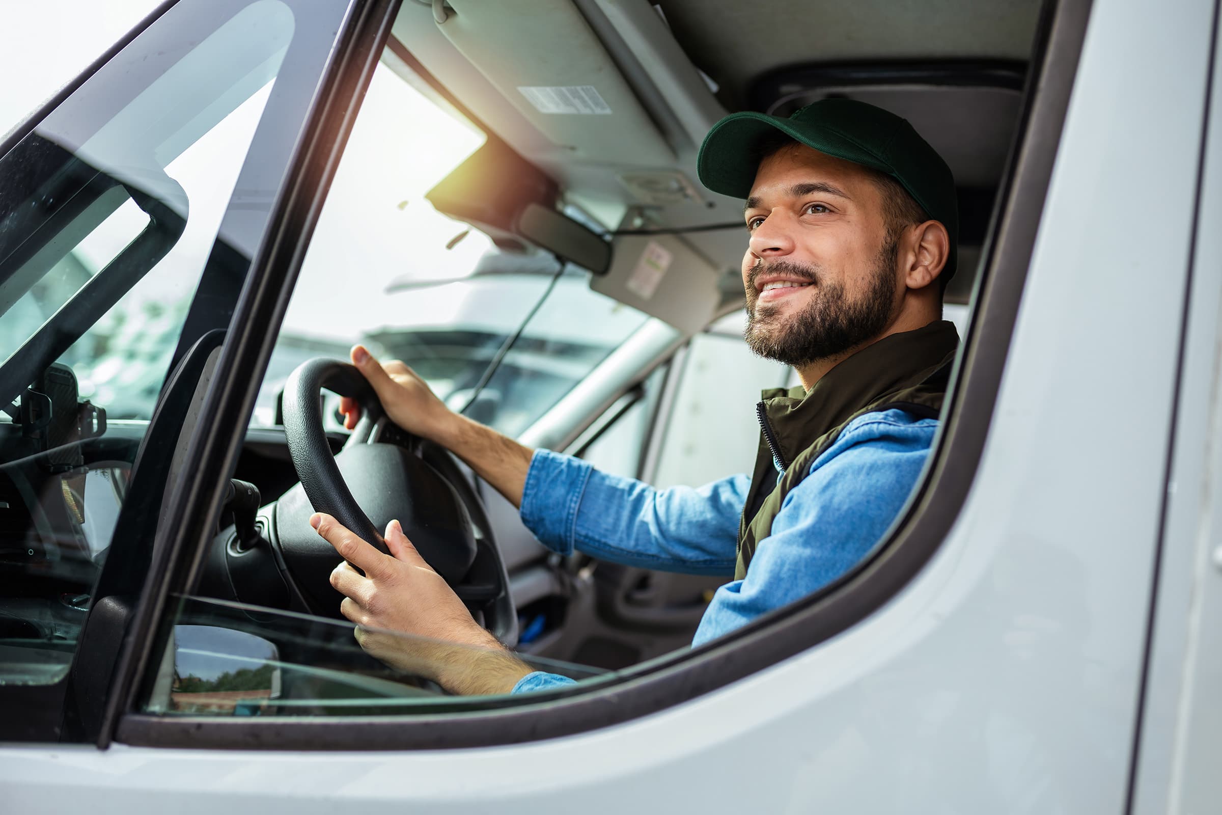 Male fleet operator smiling in vehicle, glancing out window