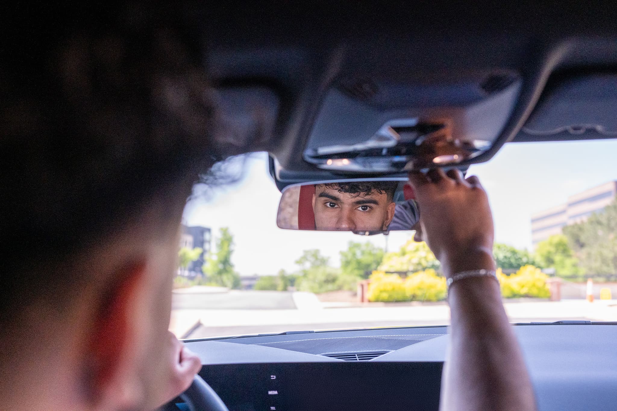 Man adjusting rearview mirror in car